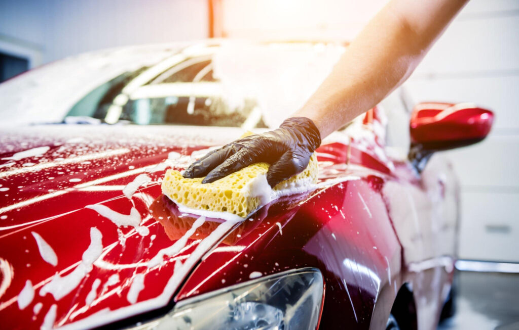 Detailer applying ceramic spray sealant to a car exterior panel with a microfibre applicator